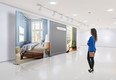In a exhibition centre, Lonely young woman wears blue jacket and visits an art exhibition and watches artist's collection on the wall. Lightened white blank walls are ready for your designs or paintings,